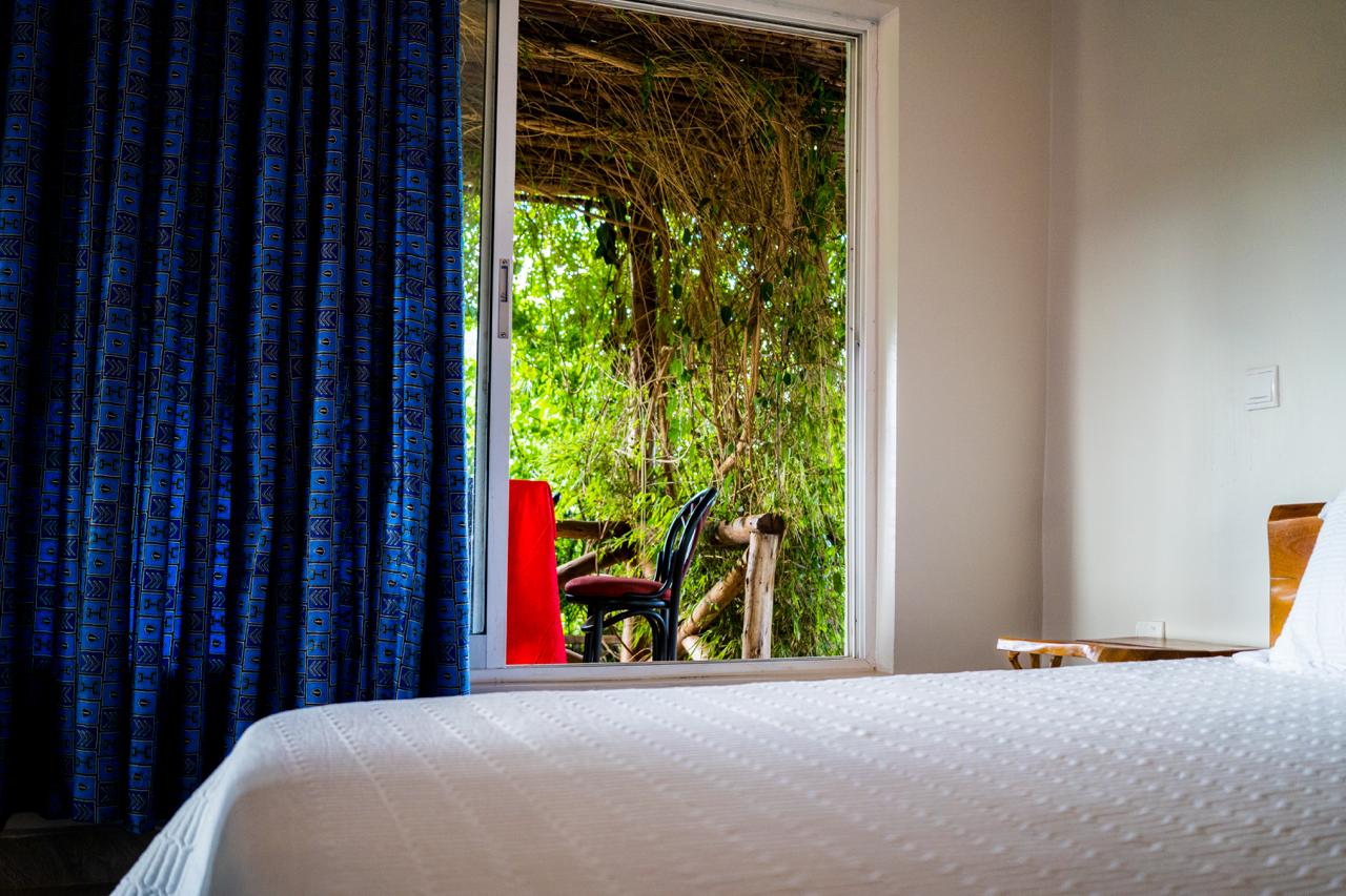 Bedroom opening onto a shaded terrace with tropical foliage