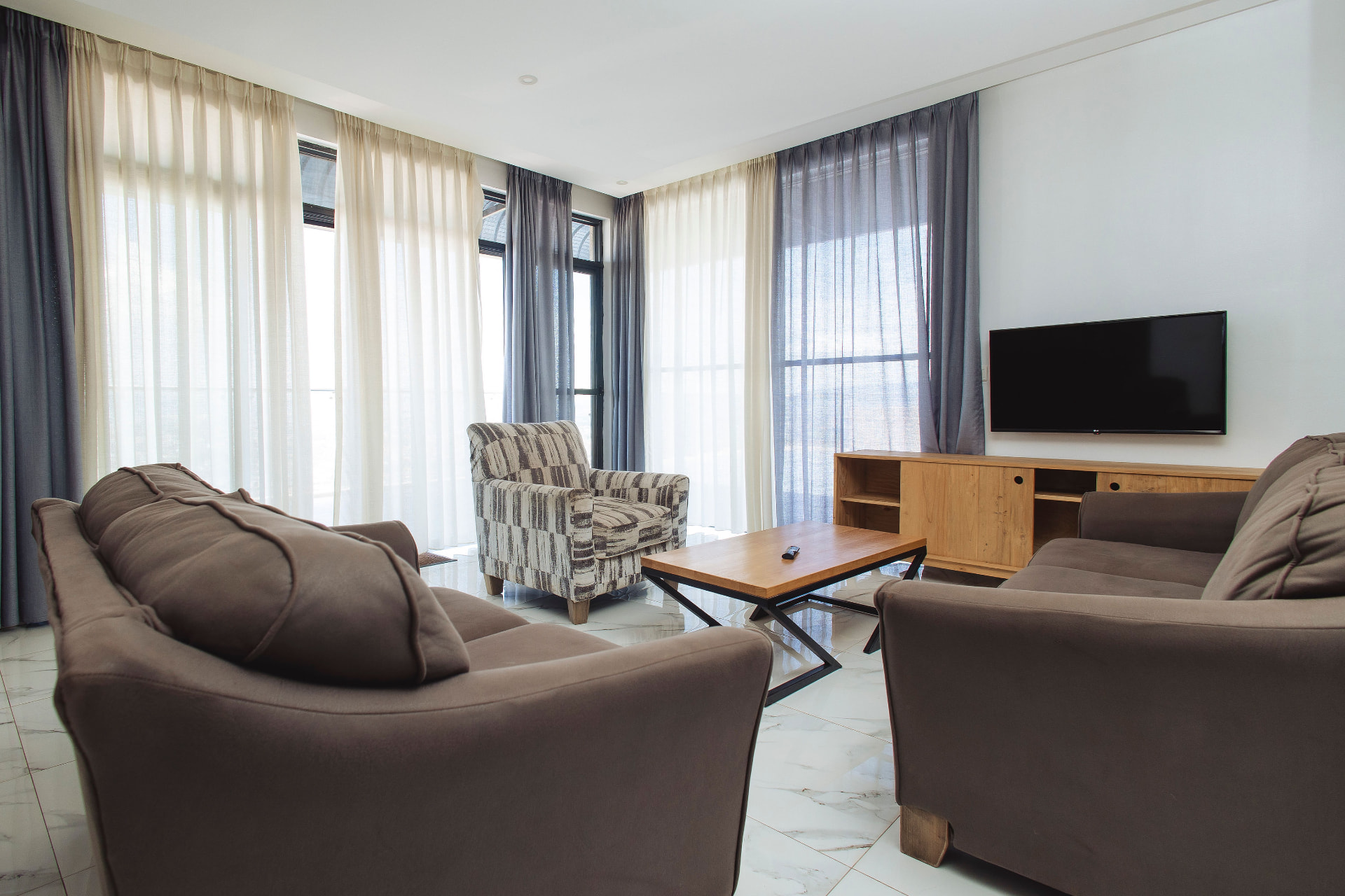 Bright living room with sofas and floor-to-ceiling curtains